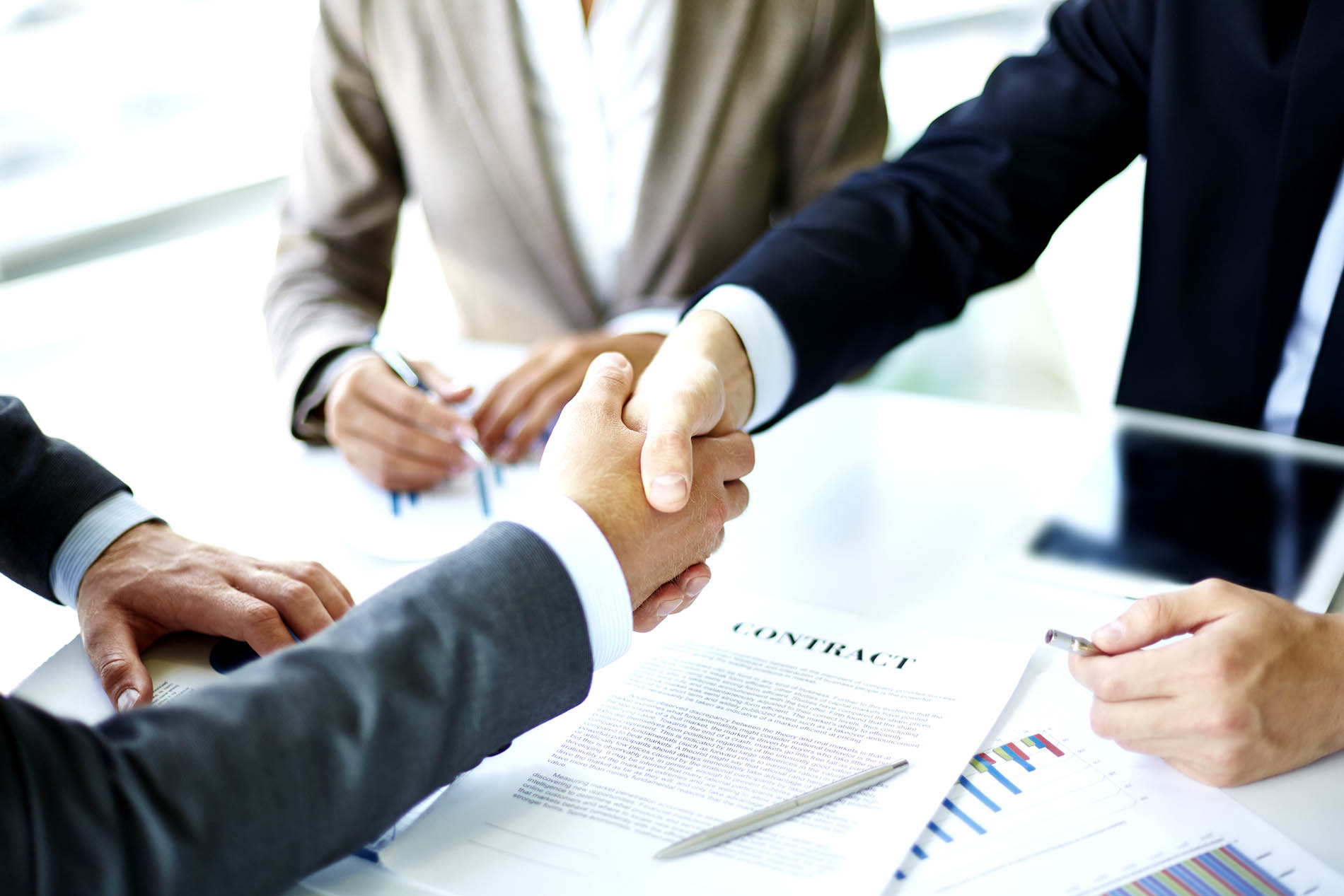Two business people shaking hands over a signed contract