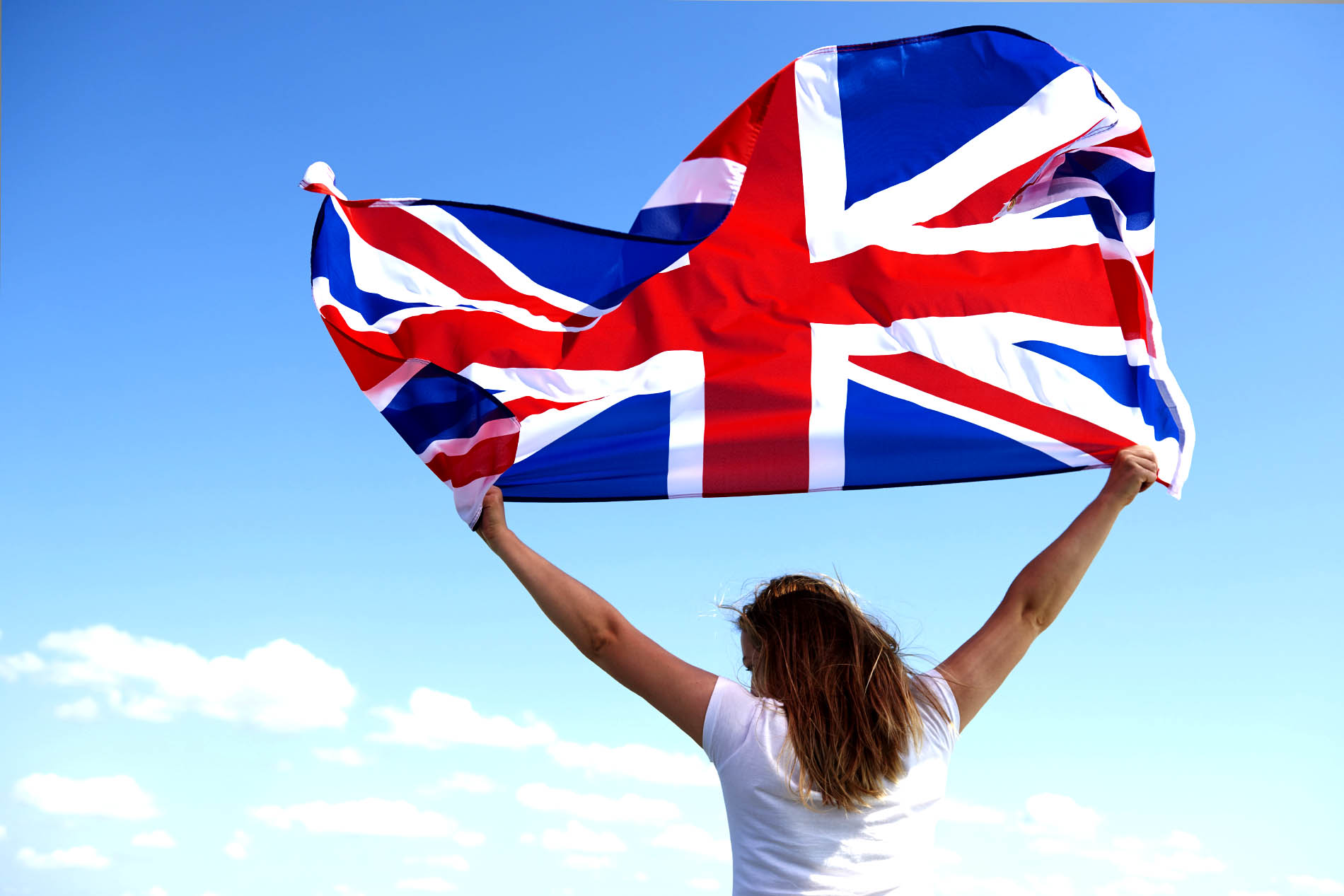 Person holding a Union Jack flag against a blue sky
